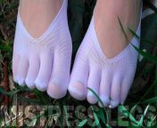 Goddess Feet in cute white socks with jeans on the spring grass field from grass field